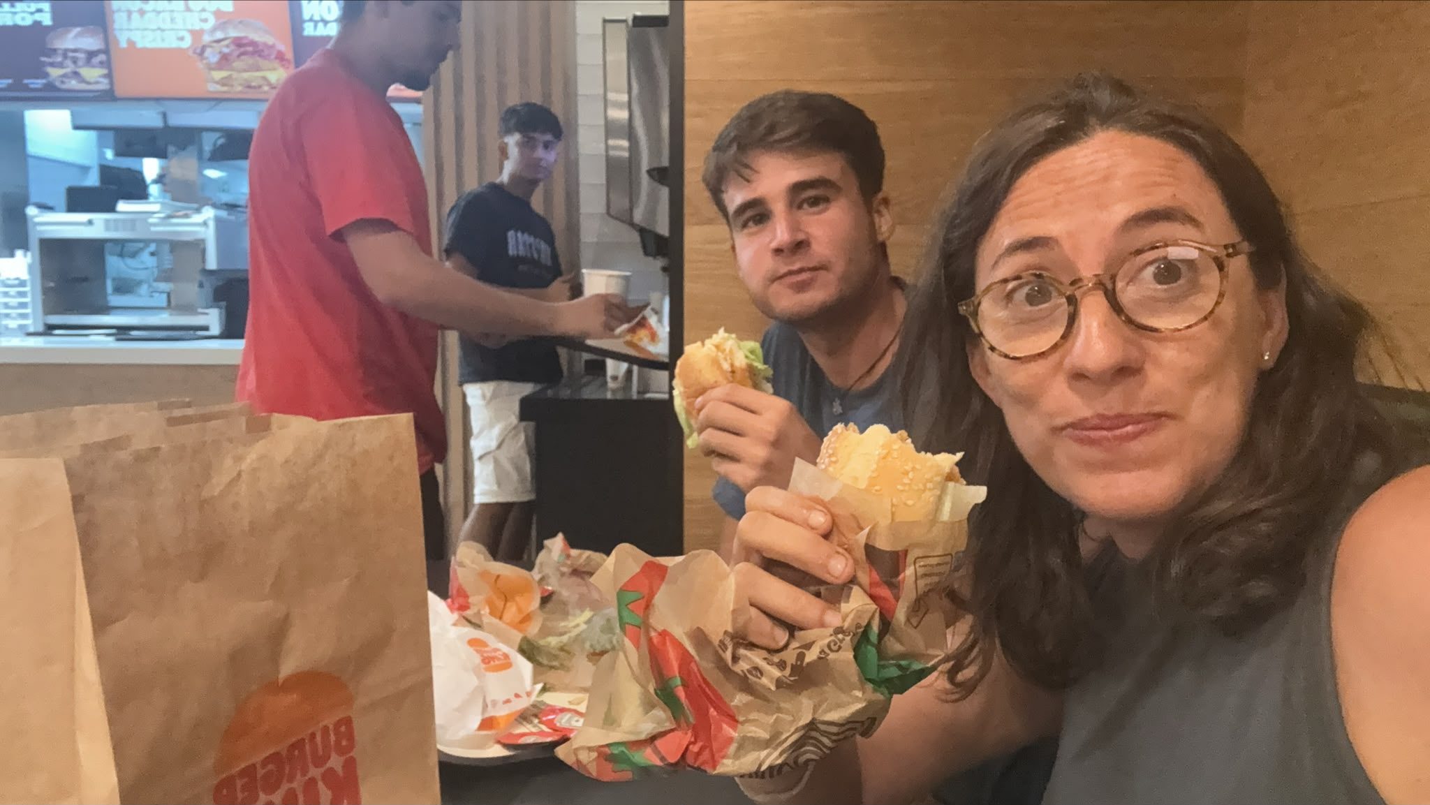 Dos personas sostienen hamburguesas en un local de comida rápida