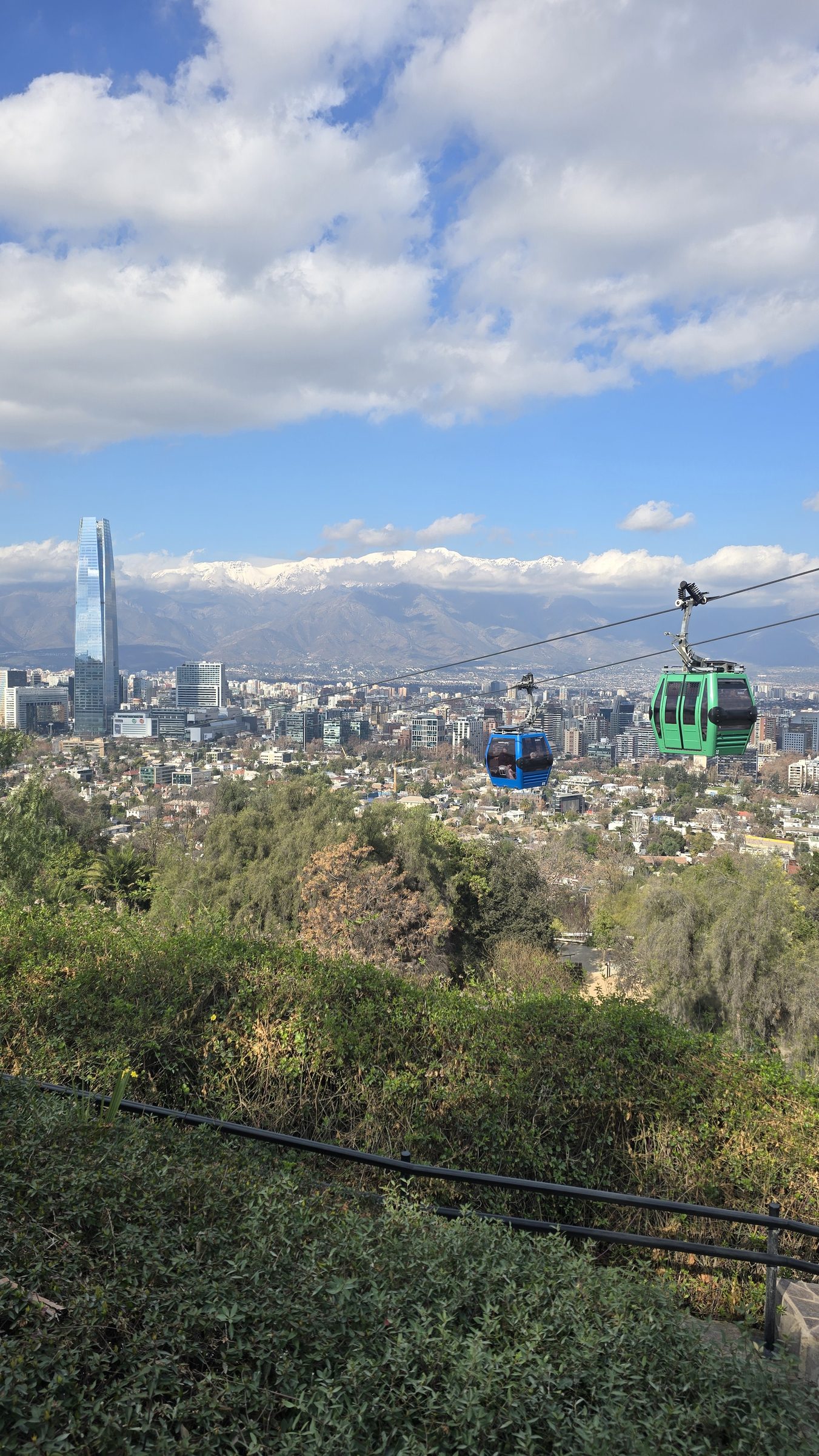 Vista de Santiago y la cordillera desde el cerro, con dos cabinas de teleférico en primer plano