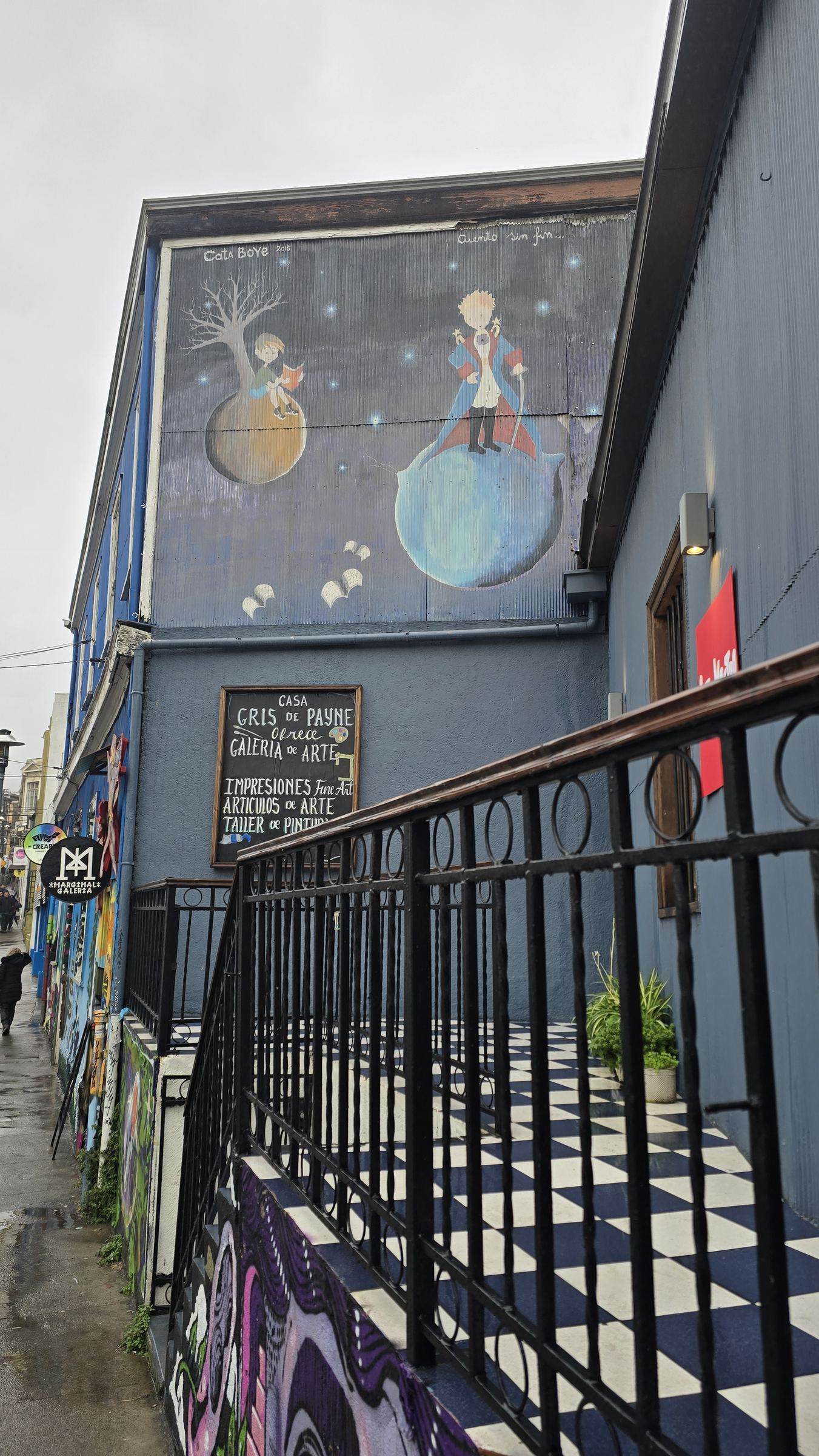 La fachada de una galería de arte con un mural, y un cartel que anuncia «Casa Gris de Payne»