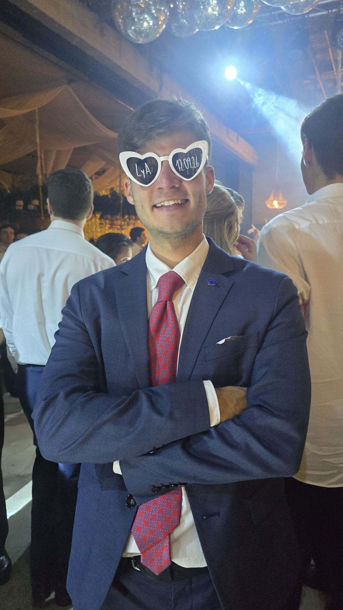 Un invitado con gafas de fiesta en forma de corazón, bailando bajo luces de discoteca